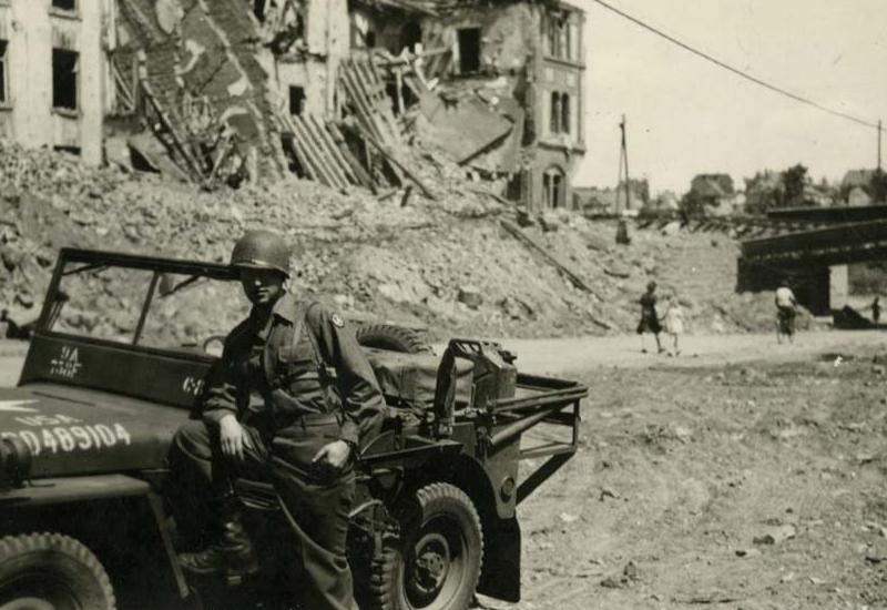 ליאו בילט חייל יהודי אמריקאי לצד גיפ צבאי בין הריסות, בזמן השחרור, גרמניה