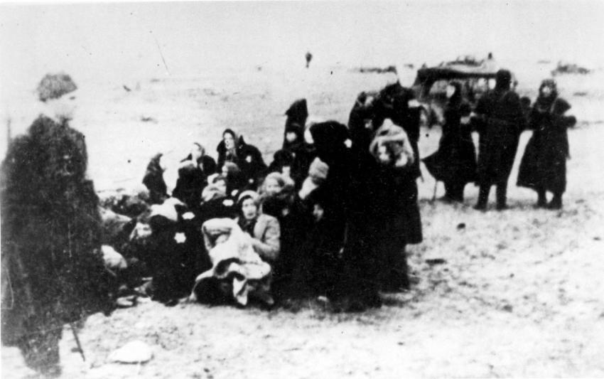 איסוף יהודים לקראת רציחתם בכפר הדיג שקדן (Skeden), לחוף הים הבלטי, 15 ק&quot;מ מצפון ללייפאיה, בדצמבר 1941 על ידי גרמנים ולטבים. משמאל – חייל לטבי.