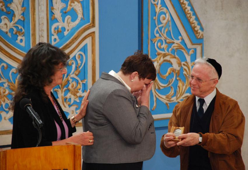 Member of the Commission for the designation of the Righteous Dr. Ehud Loeb presenting the medal and certificate of honor to  Malgorzata-Ana Gronek along with the director of the Righteous department, Irena Steinfeldt, at the Synaogue in Yad Vashem