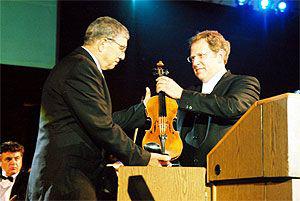Shlomo Mintz (right), violinist and conductor, presents violin from the Holocaust period to Avner Shalev, Chairman of the Yad Vashem Directorate, during the opening ceremony marking Yad Vashem's Jubilee Year