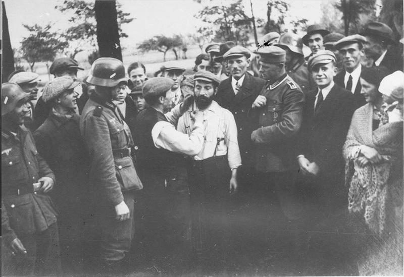 חיילים גרמנים מאלצים יהודי לגלח זקן של יהודי אחר לעיני המקומיים, ספטמבר-אוקטובר 1939, ורשה, פולין