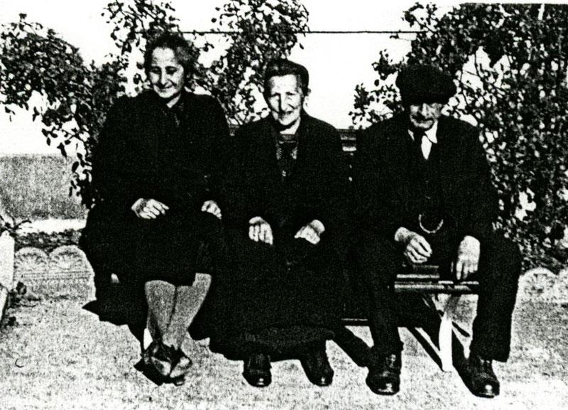 Bertha Weinschenk sitting on a park bench between two other survivors