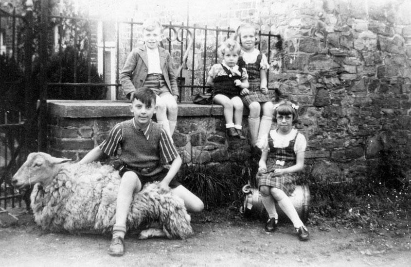 Der Gerettete Dan Dagan (Haberkorn), auf dem Schaf sitzend, mit den Kindern seiner Retter, des Ehepaars Brandt, vor dem Bauernhof der Familie, 1944