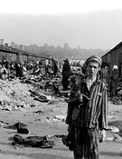 Bergen-Belsen, Németország, 1945, egy volt táborlakó a tábori barakok mellett
