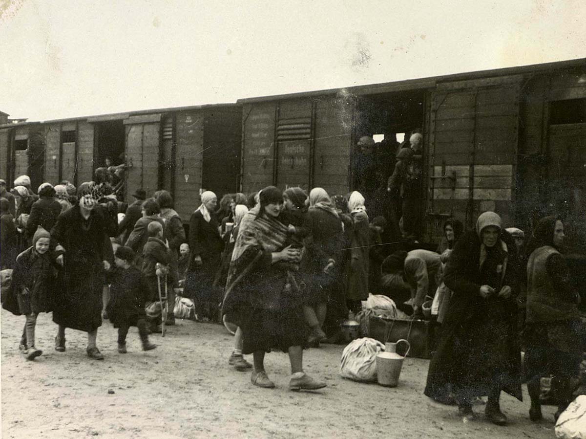 Женщины и дети на железнодорожной платформе Биркенау, известной как «рампа». Депортированные евреи проходили здесь селекцию:одних сразу же посылали на смерть, других отправляли на принудительные работы. 