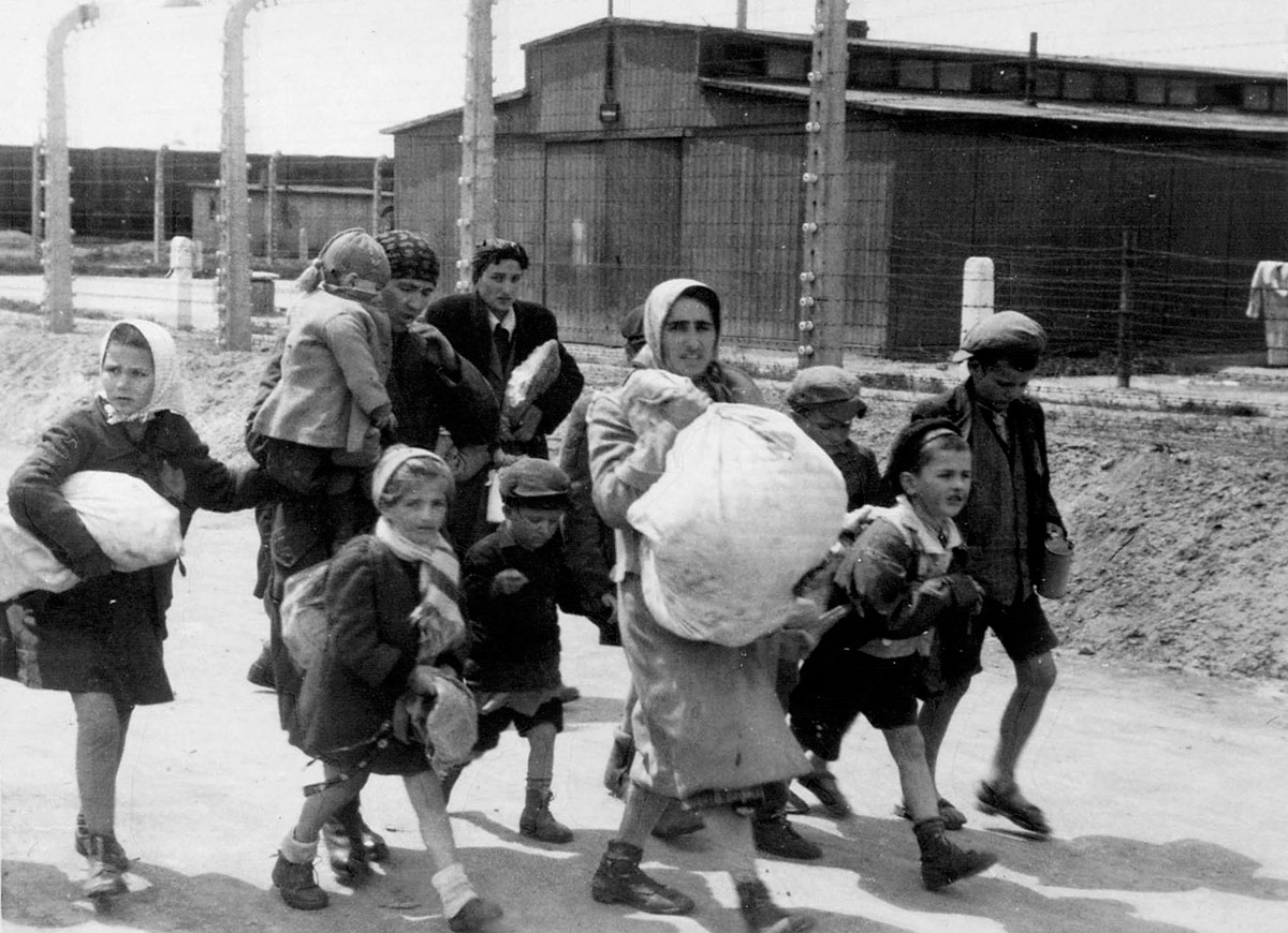 Еврейские женщины и дети идут вдоль бараков лагеря к газовым камерам