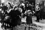חיילים גרמנים מאיימים בנשק על נשים וילדים במהלך חיסול גטו ורשה. מתחת לתצלום המקורי באוסף שטרופ נרשם: "הוצאו בכוח מהבונקרים"